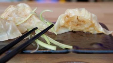 Geleneksel Asya mantısı Jiaozi ya da Gyoza tabağında. Çubuklu kızarmış hamur köftelerinin yakın çekimi. Japon yemeği.