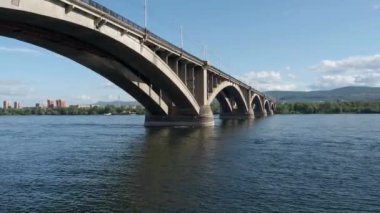 Güneşli yaz günlerinde Krasnoyarsk 'ın ortak köprüsü. Yenisei nehri ve halk köprüsü. Video 4k çözünürlüğü