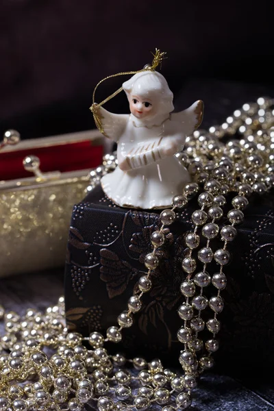 Ceramic angel standing on the old book with golden, shiny, red purse — Stock Photo, Image