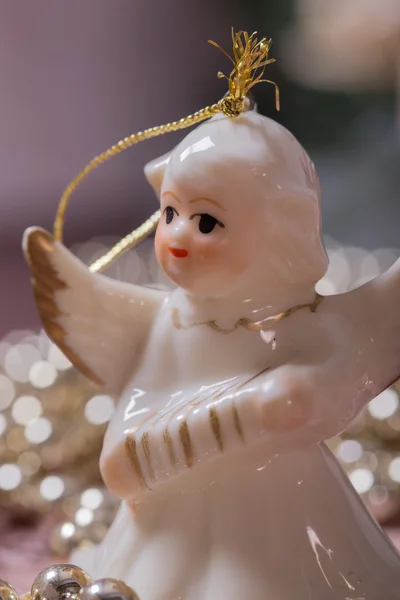 Seramik melek ve ahşap masanın üzerinde yatan altın, parlak Noel zinciri