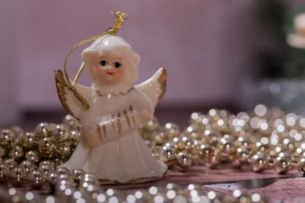 Ángel de cerámica y oro, brillante cadena de Navidad acostado en la mesa de madera — Foto de Stock