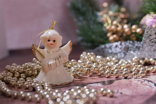 Seramik melek ve ahşap masanın üzerinde yatan altın, parlak Noel zinciri