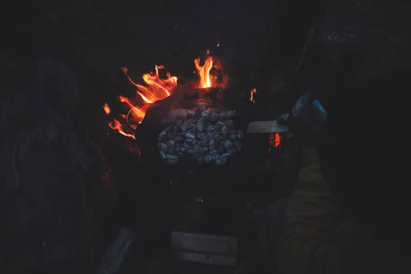 People cook food, meat in the mountains on a frying pan on the fire. Tourists at night.
