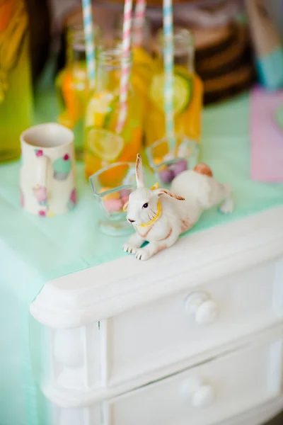 Figura de um coelho na mesa com copos de suco . Fotos De Bancos De Imagens