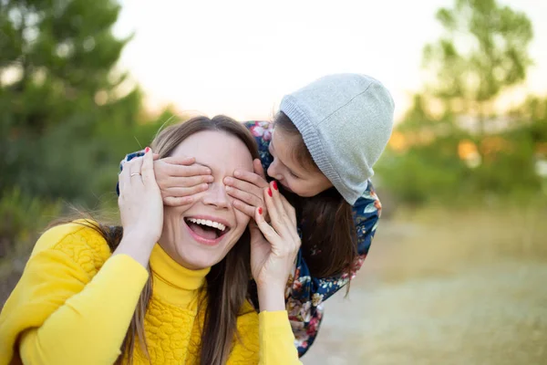Šťastná mladá dívka, smějící se, zakrývající oči své matky rukou. — Stock fotografie