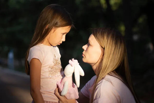 Joven madre abrazando a su pequeña hija llorando. Triste hija en brazos de sus madres — Foto de Stock