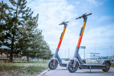 Otoparkta arka arkaya elektrikli scooterlar. Şehir bisiklet kiralama sistemi, sokakta halka açık scooter 'lar.