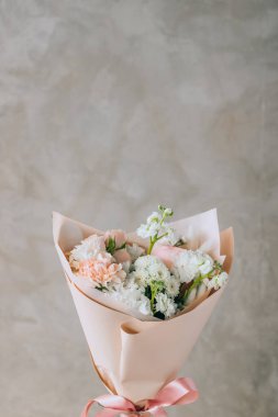 Bouquet of white freesias, carnations and chrysanthemums with pink roses and carnations in a pink package with a ribbon. Summer background