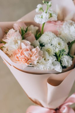 Bouquet of white freesias, carnations and chrysanthemums with pink roses and carnations in a pink package with a ribbon. Summer background