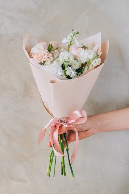 Bouquet of white freesias, carnations and chrysanthemums with pink roses and carnations in a pink package with a ribbon. Summer background