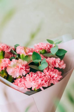 Delicate bouquet of coral carnations with eucalyptus greens with green bokeh. Summer background