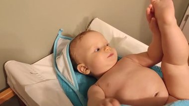 Bebek bebek çocuk masada uzanıyor, mutlu bir şekilde gülüyor ve oyun oynuyor.