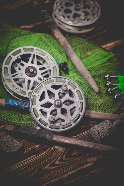 Old rarity bottom fishing reels on a wooden background. Bell, fish tank and makuha cubes. Studio photo.