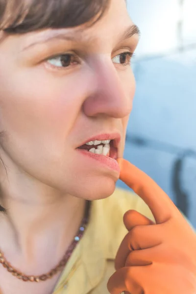 Woman in gloves shows her crooked teeth