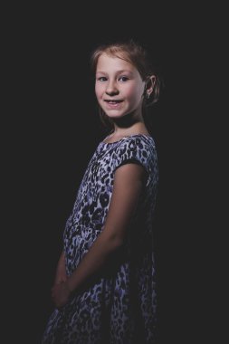 Siyah arka planda küçük tatlı bir kızın portresi. Gösterişsiz stüdyo fotoğrafı.