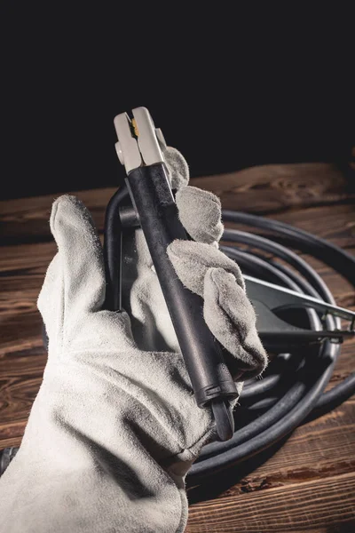 The welder in white welding leather gloves holds a wire with an electrode holder in his hand. Studio photo in hard light.