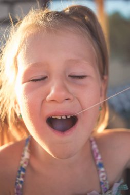 Bir bebek dişini iplik kullanarak çıkarma işlemi.