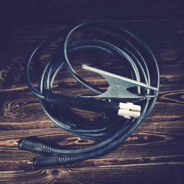 Ahşap bir arka planda kaynak kabloları. Stüdyo fotoğrafı sert ışıkta.