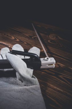 Kaynak elektrotunun elektrot tutucusu, tahta bir arka planda kaynak eldiveninin içinde yatıyor. Stüdyo fotoğrafı sert ışıkta.