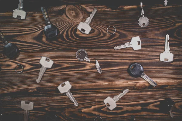 A studio photo of a broken key among many normal keys on a wooden background. Photo in the old style with vignetting.