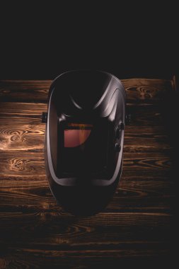 Ahşap bir arka planda siyah kaynak maskesi. Sert ışıklandırmalı bir stüdyo fotoğrafı..