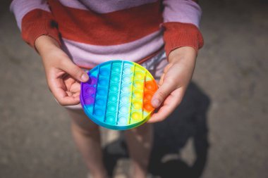 Doğada poz veren küçük tatlı bir kız elinde anti-stres oyuncağıyla.