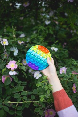 Küçük tatlı bir kız elinde parlak, renkli bir anti-stres oyuncağı tutuyor..