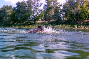 Genç adam nehirde yüzüyor..