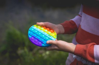Doğada poz veren küçük tatlı bir kız elinde anti-stres oyuncağıyla.
