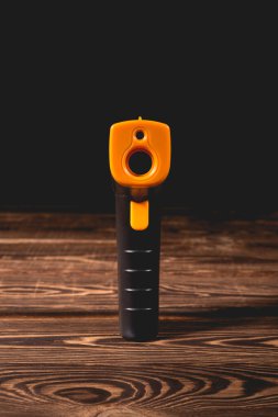 Ahşap arka planda sarı-siyah pirometre. Temassız sıcaklık ölçümü için bir cihaz. Stüdyo fotoğrafı.