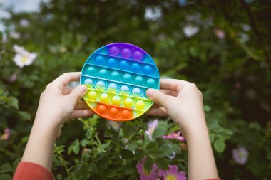 Küçük tatlı bir kız elinde parlak, renkli bir anti-stres oyuncağı tutuyor..