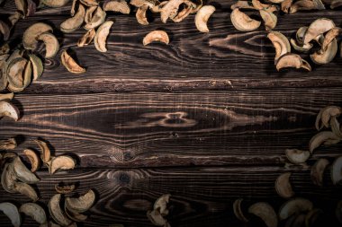 Ahşap bir arka planda kurumuş elma dilimleri. Sert ışıklandırmalı bir stüdyo fotoğrafı..