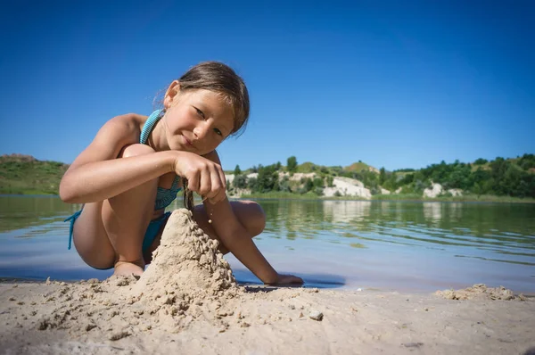 Uma Menina Fofa Maiô Está Construindo Castelo Areia Costa Lago — Fotografia de Stock