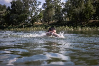 Genç adam nehirde yüzüyor..