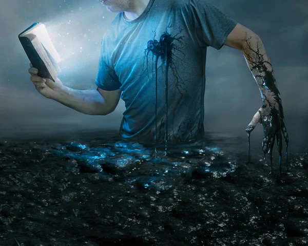 一个男人举着一本发光的圣经来揭示他在黑暗中的处境 免版税图库照片