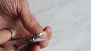 Adam orta parmağında makasla bir tırnak kesiyor.