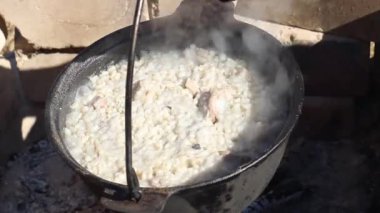 Dökme demirden bir kazanda et kaynayan inci arpası, yakın plan.