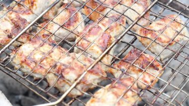 Kömürlerin üstündeki ızgarada ızgara var. Duman var, yağ var, yakın plan.