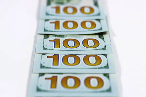 100 dolarlık banknotlar beyaz arka planda yatıyor.