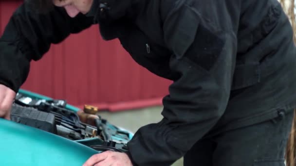 Un homme en vêtements noirs creuse dans le capot ouvert d'une voiture — Video