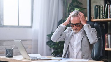 Gözlüklü yetişkin işadamı raporla uğraşırken sorunları çözmekle şaşkına döndü. İş konsepti. Boşluğu kopyala