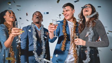 Gri arka planda izole bir şekilde Noel 'i birlikte kutlarken düşmüş konfeti gibi bakan şaşırmış arkadaşların beline kadar.