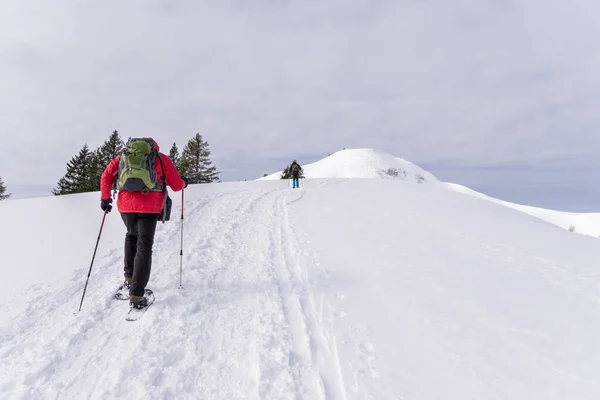 stock image Senior couple is snowshoe hiking in alpine snow winter mountains. Allgau, Bavaria, Germany.