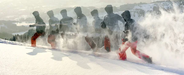 Glücklicher Mann mit Kapuze, der mit Schneeschuhen durch tiefen Pulverschnee läuft. Schnee spritzt und spritzt. Mehrfachbelichtung. — Stockfoto