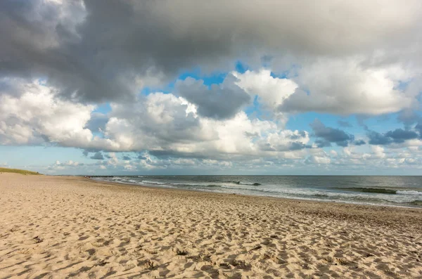 Sand am Strand mit blauem Himmel und dramatischen Wolken am Ufer im sanften Abendsonnenuntergang. Hvidbjerg Strand, Blavand, Nordsee, Dänemark. — Stockfoto