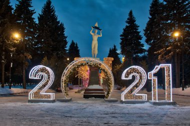 2021 yılbaşı tabelası ve alacakaranlıktaki Northen River İstasyonu 'nun girişinde kafasında yelkenli taşıyan bir kızın heykeli. MOSCOW, Rusya - 05 Şubat 2021
