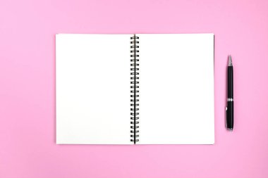 Pembe arka planda spiral defter ve kalem aç