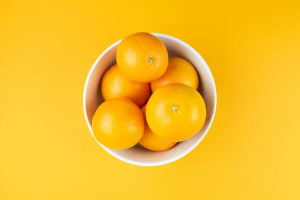 Diretamente acima vista de tigela branca cheia de laranjas suculentas — Fotografia de Stock