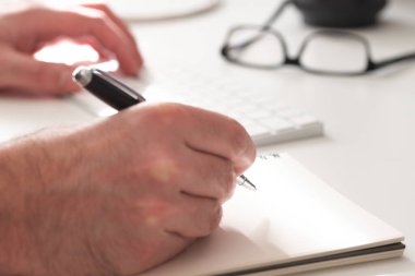 Not alan kişinin elleri bilgisayar klavyesinde beyaz yazı yazarken yakın plan görüntüsü