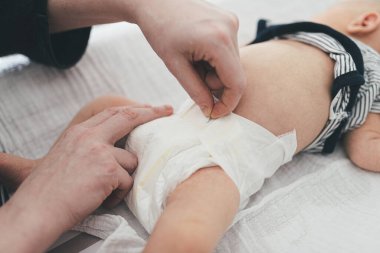 Ebeveynler yeni doğmuş bir bebeğin altını değiştiriyor.